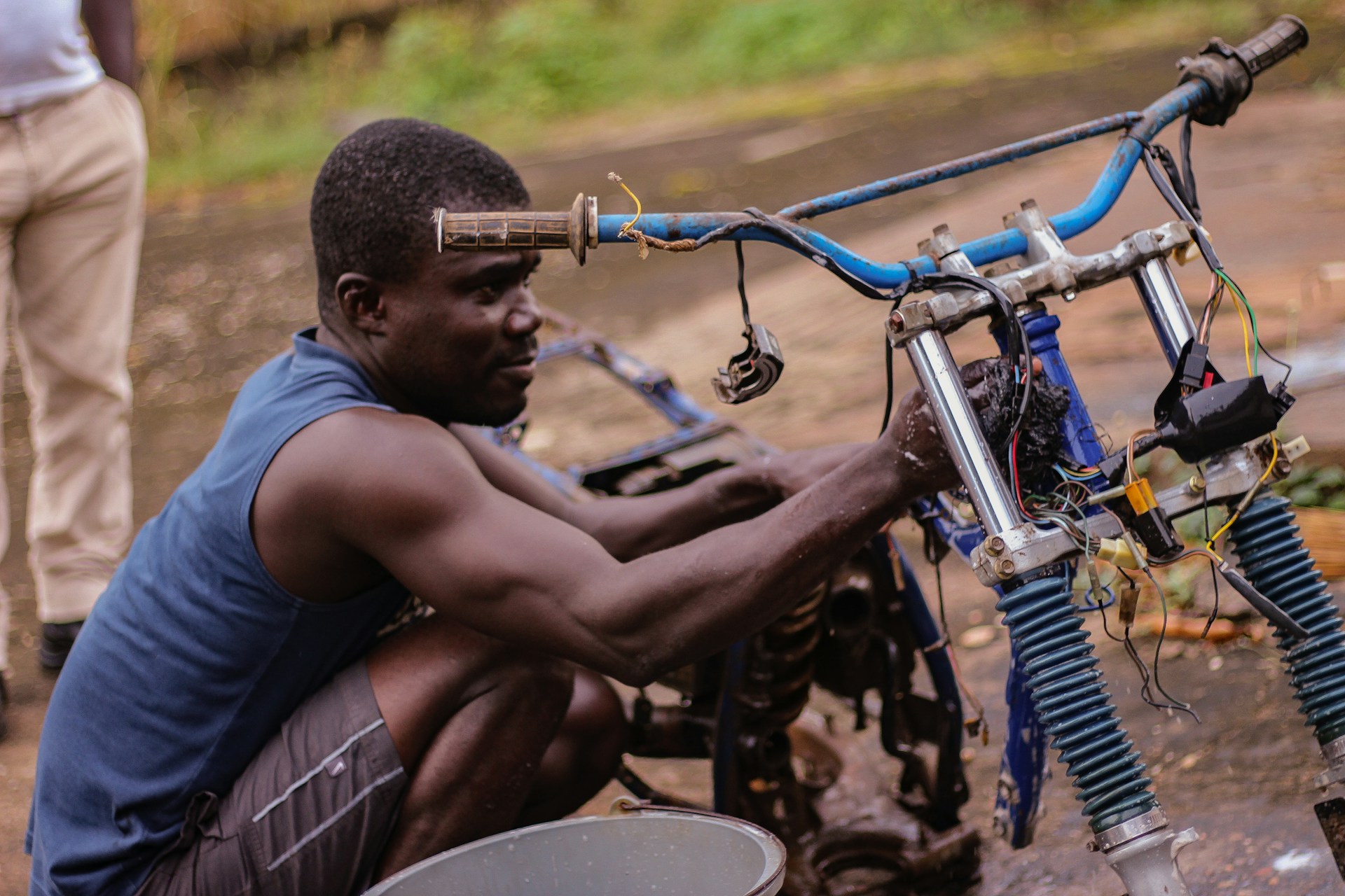 A young man repairing a motorcycle engine by hand